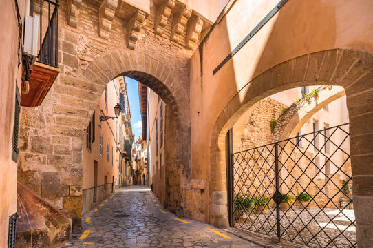 Idyllic narrow street with gate of Almudaina at the old historic city center of Palma de Mallorca