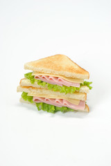 A classic sandwich with ham, cheese and lettuce leaves. Slices of white bread are roasted. Vertical orientation of the frame. White background.