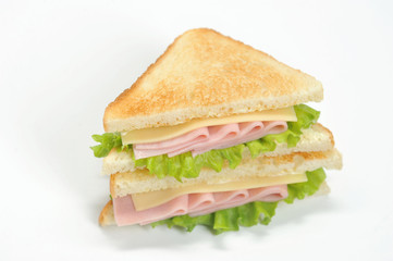 A classic sandwich with ham, cheese and lettuce leaves. Slices of white bread are roasted. White background. Close-up. Macro photography.