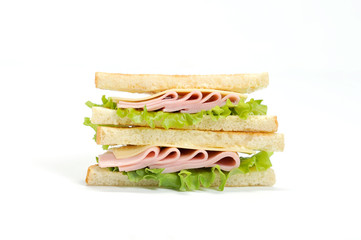 A triangular shape sandwich on a white background. The filling of the sandwich consists of lettuce, ham, cheese and fresh vegetables. Close-up.