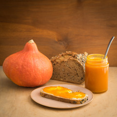 Pumpkin jam in a jar with fresh wholegrain bread and butter