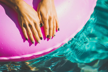 woman manicured hands laying on the rubber ring in the swimming pool. Summer Vacation. Enjoying...