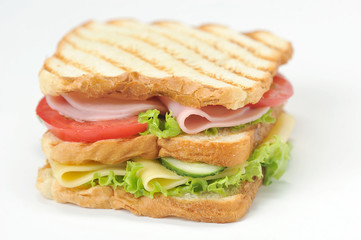Club sandwich of fried white bread. The filling of the sandwich consists of slices of cheese, ham, ripe tomato, fresh cucumber and lettuce leaves. White background. Close-up. Macro photography.