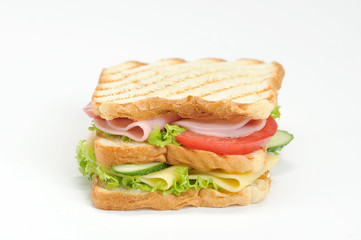 Club-sandwich of white bread. The filling of the sandwich consists of slices of cheese, ham, ripe tomato, fresh cucumber and lettuce leaves. The bread is cooked on the grill. White background. Closeup