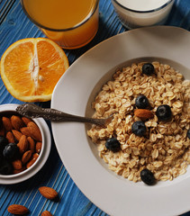 Healthy eating, food and diet concept - tasty oatmeal with berries and glass of orange juice. Top view. Blue wooden background.