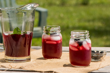Cannine jars of fruit tea with pitcher on picnic table
