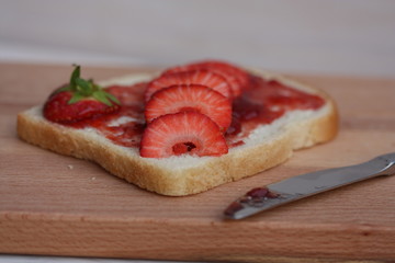 Bread slice with jam and strawberries.