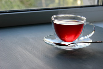 Insulated Cup of fragrant hot tea in a glass transparent Cup on the windowsill