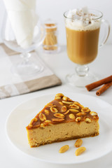 Slice of caramel cake with peanuts and a cup of coffee with cream