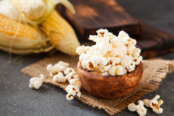 Popcorn in a olive wooden bowl on a dark background