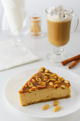 Slice of caramel cake with peanuts and a cup of coffee with cream
