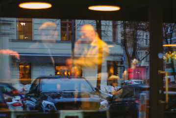 Blurred image Business Meeting two men photographed through the window of a cafe. In window reflected the parked cars and cityscape.