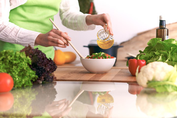 Close Up of human hands cooking vegetable salad in kitchen on the glass table with reflection. Healthy meal, and vegetarian food concept