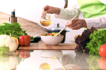 Close Up of human hands cooking vegetable salad in kitchen on the glass table with reflection. Healthy meal, and vegetarian food concept