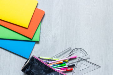 Colorful notebooks with stationery in open pencil case next to