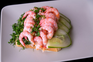 Shrimp sandwich on a plate with lights in the background