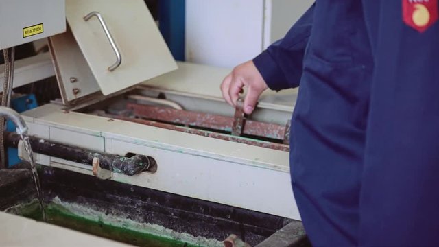 Factory worker processes parts in a chemical bath. Production. Industry.