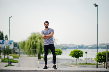 Handsome tall arabian beard man model at stripped shirt posed outdoor at skate park. Fashionable...