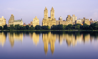 Fototapeta na wymiar Manhattan skyline viewed from Central Park, New York featuring lake and city reflection on the foreground