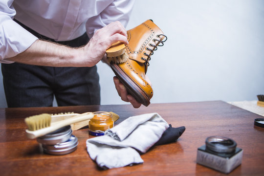 Professional Male Shoes Cleaner Using Brush For Polishing Male Tan Brogue Derby Boots. Variety of Cleaning Accessories Used.