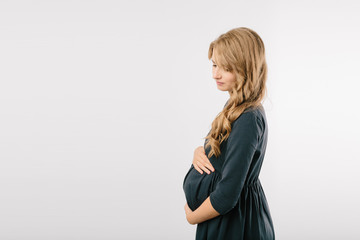 Young pregnant woman in black dress over white background in studio