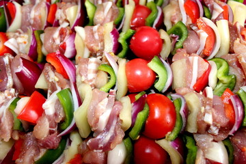 Freshly prepared meat and vegetable healthy kebabs ready for grilling, containing fresh tomatoes, red and green paprika, onions, bacon and meat