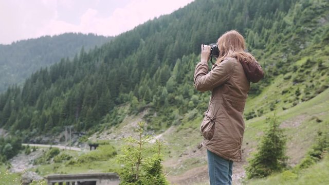 A young woman hiker climbs mountains with photo camera. Transfagarasan, Carpathian mountains in Romania