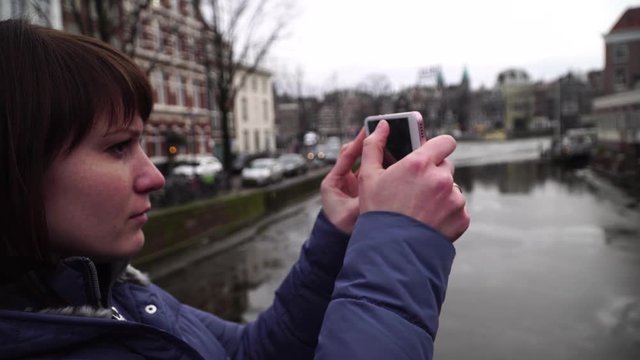 Woman tourist takes pictureson on smartphone in Amsterdam.