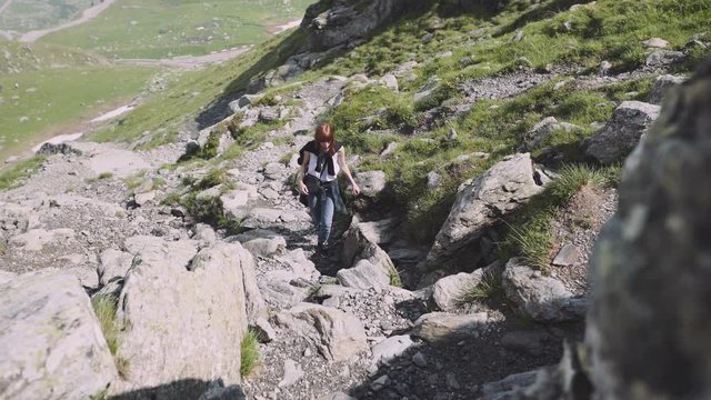 A young woman hiker climbs mountains with photo camera. Transfagarasan, Carpathian mountains in Romania