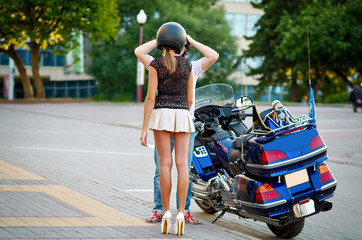 Man puts on motorcycle helmet on fellow traveler. Long legged woman wear safety helmet before travel on motor bike. Safe driving concept.