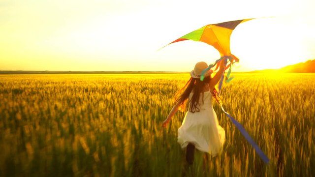 girl running around with a kite on the field.