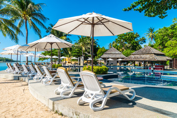 Beautiful tropical beach and sea with umbrella and chair around swimming pool
