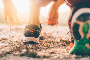 Woman wear running shoe on to walking and running on nature green background. Health exercise concept.