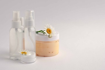 Fototapeta na wymiar Cosmetic bottle containers with camomole flowers, Blank label package for branding mock-up, Natural organic beauty product concept