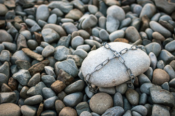 Fototapeta na wymiar A huge stone tied with a metal chain