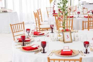 Beautiful banquet hall under a tent for a wedding reception. Interior of a wedding tent decoration ready for guests. Decor flowers. Red theme
