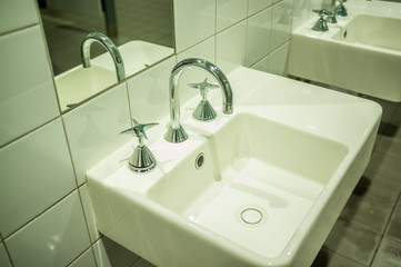 Closeup of white sink with stylish tap in public restroom