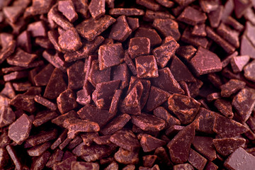 Dark chocolate pieces background, copy space. Closeup of pile chocolate candies. Candy texture. Candy pattern. Sweets background. Abstract background. Top view, flat lay