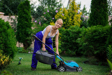 Gardener girl is cutting the grass with the mower