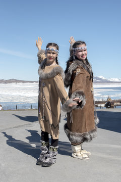 Two chukchi girls in folk dress show figure of traditional dance against the Arctic landscape