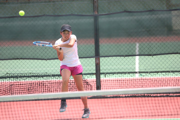 バックハンドを打つ女子ジュニアテニスプレイヤー