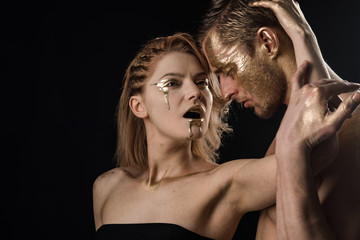 Man and woman relations. man and woman embrace with golden paint makeup on body isolated on black background, copy space.