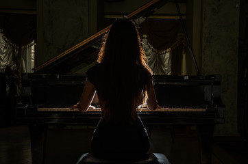 Young charming brunette girl playing the piano