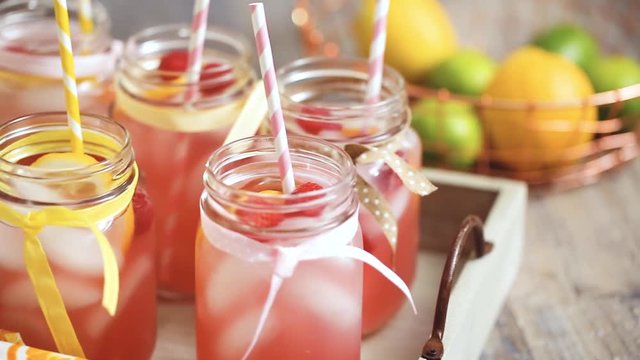 Raspberry lemonade garnished with fresh lemon and raspberries in drinking mason jars