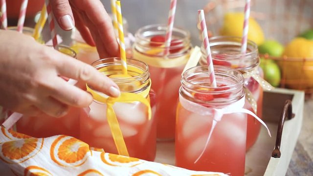 Raspberry lemonade garnished with fresh lemon and raspberries in drinking mason jars