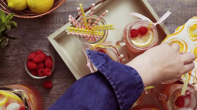 Raspberry lemonade garnished with fresh lemon and raspberries in drinking mason jars