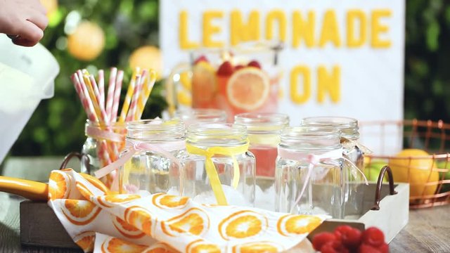 Step by step. Pouring raspberry lemonade with fresh lemons and raspberries in drinking mason jars