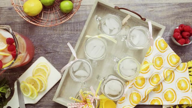 Step by step. Pouring raspberry lemonade with fresh lemons and raspberries in drinking mason jars