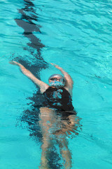 Young swimmer with silver swimming cap dive under water in the swimming pool for competition