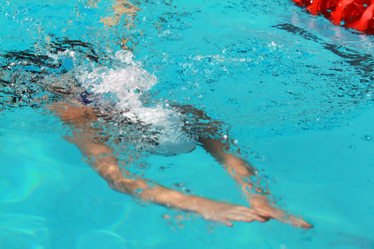 Young swimmer with white swimming cap swims breaststroke dive under water in the swimming pool for competition